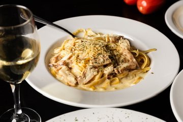 Chicken Alfredo served beside a glass of white wine at Sorriso