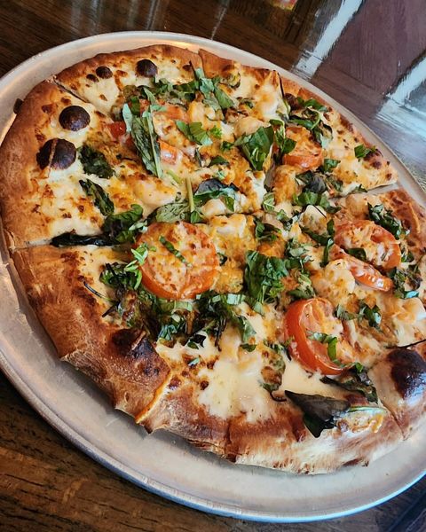 A Sorriso pizza topped with tomatoes and fresh basil