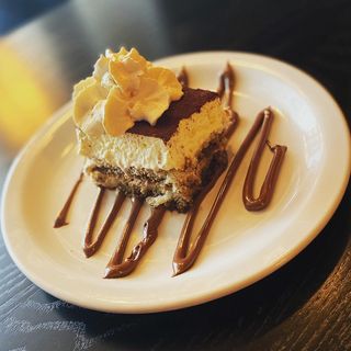 A layered dessert dusted with cocoa and topped with whipped cream
