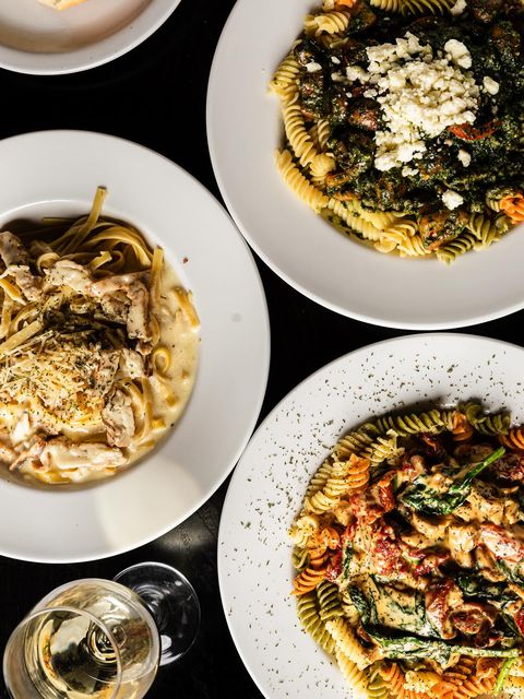 Several pasta dishes arranged around a glass of white wine